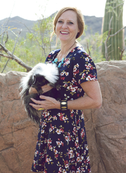 Keeper Elise models a black floral Buffalo Exchange dress with a skunk