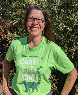 Robin stands in front of a green-leaved bush, wearing a Museum t-shirt