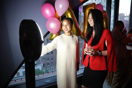 Two women use the DigiBooth while standing in front of pin balloons