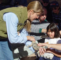 A volunteer helps children collect mineral specimens in egg cartons