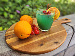 The Blue Sonoran Cocktail on a board with oranges and cherries